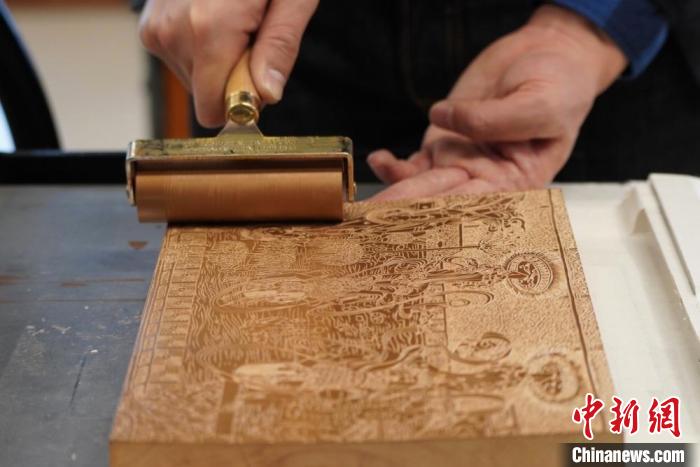 圖為徐晉林工作室工作人員正在給雕好壁畫的版面滾油墨?！【琶赖┰?　攝