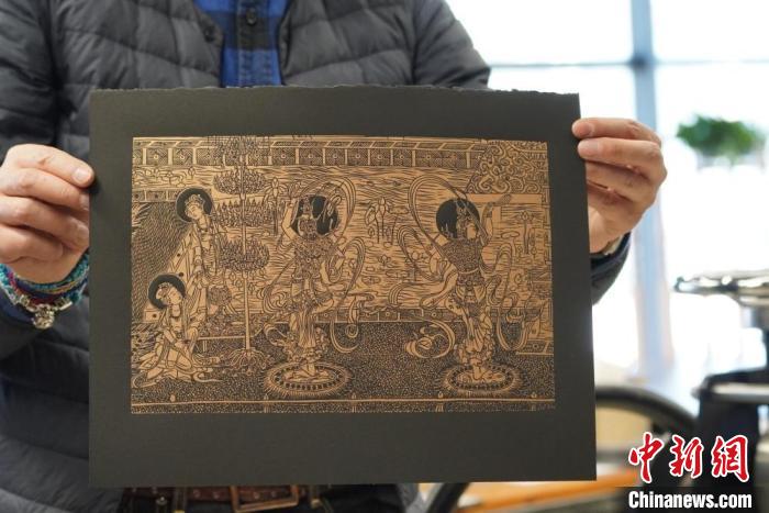 圖為手工書藝人展示敦煌雕版壁畫印刷品。　九美旦增 　攝