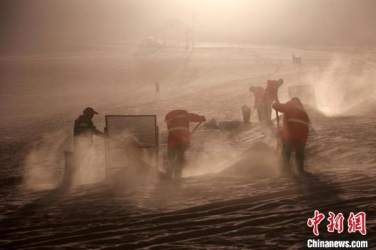 圖為敦煌市鳴沙山月牙泉景區(qū)“駱駝保姆”清理駱駝糞便。　張曉亮 攝