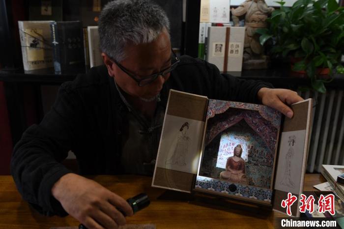 圖為讀者出版集團(tuán)讀者晉林工作室獨(dú)立出品人徐晉林，展示互動(dòng)性強(qiáng)的敦煌題材手工書。(資料圖) 楊艷敏 攝