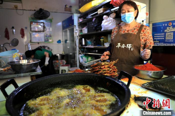 圖為平安驛·河湟民俗文化體驗地內(nèi)的商戶炸干板魚?！⊙Φ?攝
